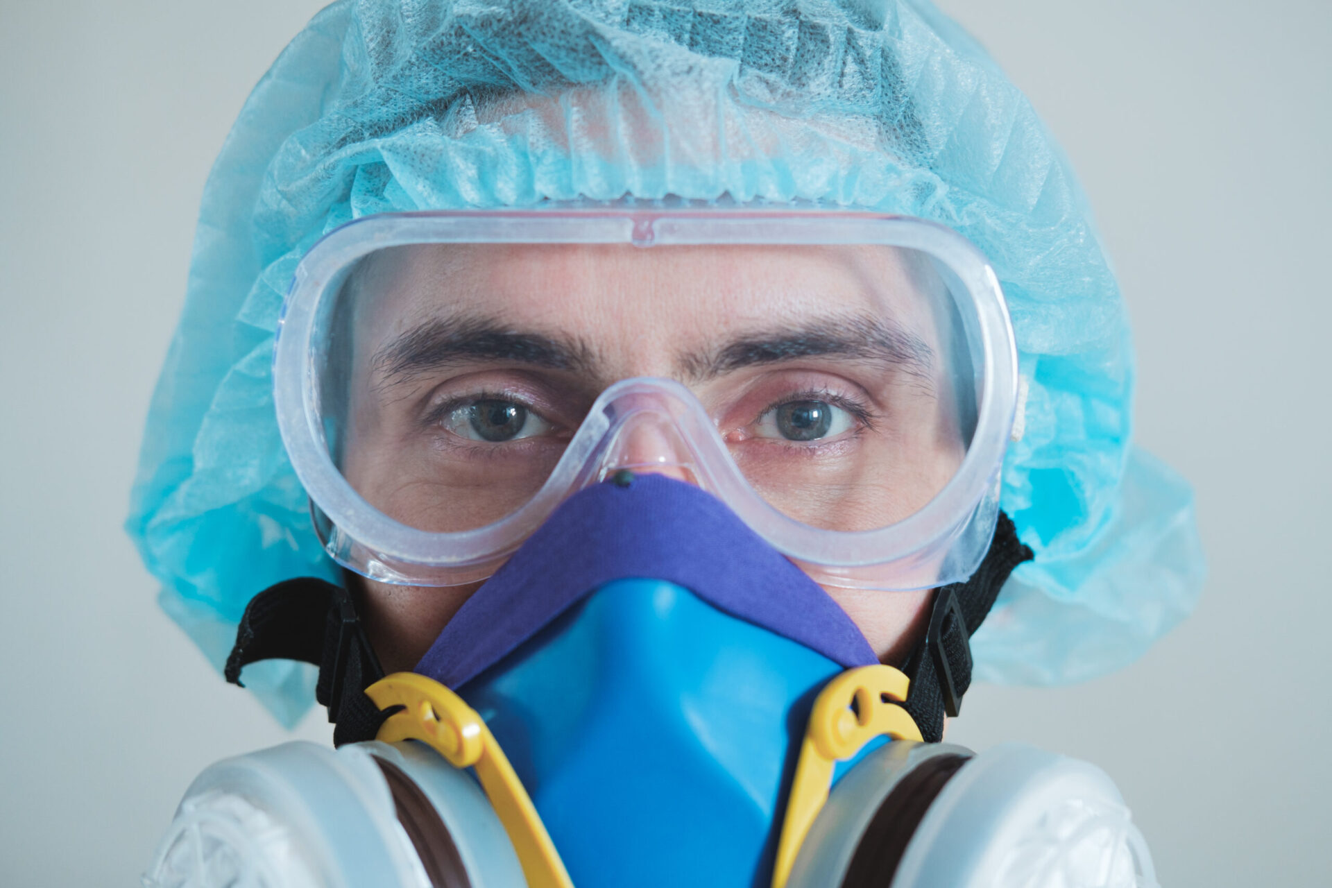 Man in protective face mask, eyeglasses and head protection, focus on eyes.